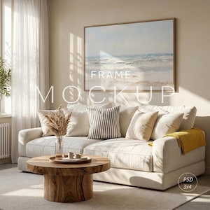 Puede incluir: Un salón con un sofá crema, cojines, una mesa de centro de madera y una obra de arte enmarcada que representa un paisaje marino. La obra de arte tiene un marco marrón claro. El texto "FRAME MOCKUP" está superpuesto.