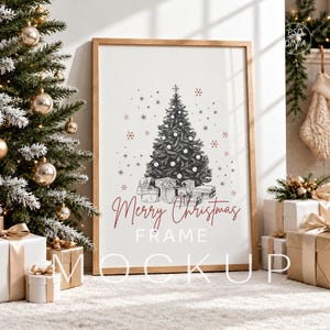 Op de afbeelding: Een verticale houten lijst met een witte print met een zwart-wit schets van een kerstboom met cadeautjes, rode en zwarte sneeuwvlokken en de rode tekst Merry Christmas FRAME MOCKUP gecentreerd op de witte achtergrond.