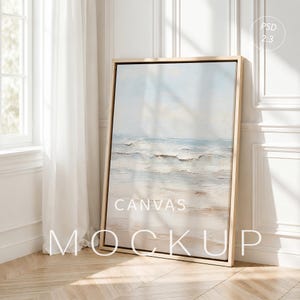 Può includere: Un mockup di tela rettangolare verticale in una cornice di legno chiaro con un dipinto astratto e materico di una spiaggia nei toni tenui del blu, bianco e beige. Il testo PSD 2:3, CANVAS e MOCKUP è sovrapposto in lettere bianche.