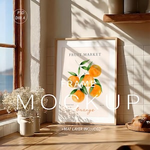 Könnte beinhalten: Ein gerahmter Kunstdruck mit einer Aquarellillustration von Orangen und grünen Blättern. Der Druck trägt die Aufschrift "FRUIT MARKET" und "Orange". Der Rahmen ist hellbraun. Die Worte "MOCK UP" sind im Vordergrund.