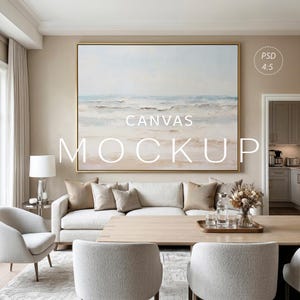 Könnte beinhalten: Ein Wohnzimmer-Interieur mit einem großen Leinwand-Mockup, das ein Landschaftsgemälde in einem goldenen Rahmen zeigt. Der Text "CANVAS MOCKUP" ist auf der Leinwand zu sehen. Der Raum umfasst ein weißes Sofa, Stühle und einen Holztisch, wodurch eine moderne, neutrale Ästhetik entsteht.