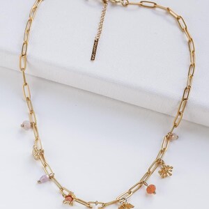 Könnte beinhalten: Eine goldene Kettenkette mit kleinen Anhängern und Perlen. Die Anhänger umfassen Blumen, Blätter und kleine Perlen in Rosa und Orange.