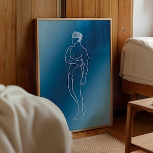 Op de afbeelding: Een ingelijste kunstdruk met een witte lijntekening van een mannelijke figuur op een blauwe gradiënt achtergrond. Het kunstwerk wordt getoond in een kamer met houten lambrisering en een bed. De lijst is licht van kleur.