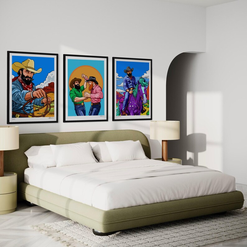 May include: Three framed art prints depicting cowboys in various scenes hang above a bed. The artwork features vibrant colors and bold lines, showcasing cowboys with hats and facial hair. The bed has a green base and white bedding.