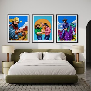 May include: Three framed art prints featuring cowboy illustrations. One shows a cowboy with a lasso, another depicts two cowboys dancing, and the third shows a cowboy riding a purple horse. The prints have black frames and are displayed above a bed.