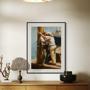May include: Framed art print depicting two men embracing on a dock. The painting shows the men in white shirts and khaki pants, with a boat in the background. The artwork is displayed on a wooden cabinet with decorative items.