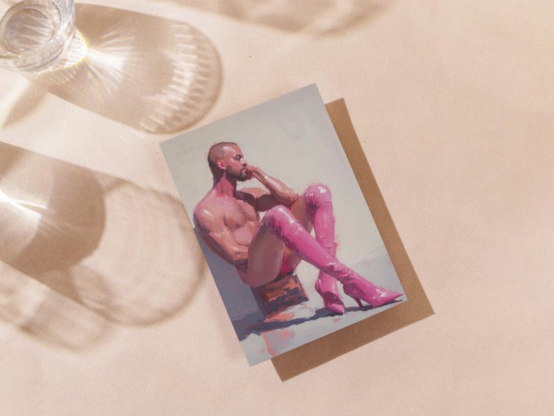 May include: Art print depicting a nude figure in pink boots, seated and leaning. The artwork is on a white background, placed on a brown card. A glass of water is in the upper left corner, casting a shadow across the surface.
