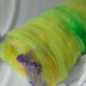 May include: A roll of yellow, green, and purple wool roving. The roving is a blend of different colors and textures.