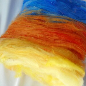 May include: A bundle of colorful, hand-dyed fiber in shades of yellow, orange, and blue. The fiber is soft and fluffy, and it would be perfect for spinning or felting.