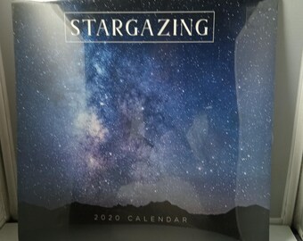 Może przedstawiać: Kalendarz na rok 2020 z motywem nocnego nieba. Okładka zawiera napis "STARGAZING" w białym prostokącie nad żywym obrazem gwieździstej galaktyki. Na dole kalendarza widnieje napis "2020 CALENDAR".