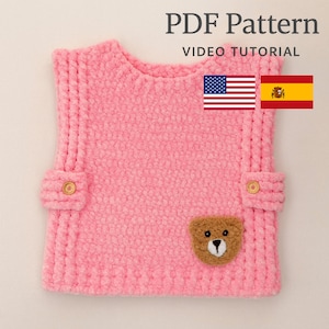 Op de afbeelding: Een roze gebreid babyvestje met een teddybeer applicatie. Het vestje heeft twee kleine zakken met houten knopen en is gelabeld "PDF Pattern VIDEO TUTORIAL" met de Amerikaanse en Spaanse vlaggen.