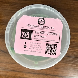May include: A pink container with a green soap bar inside. The label reads "Jehovah Products, A Subsidiary of Fihaj LTD, Satanic Curses Breaker (Very Powerful Spiritual Soap)". It also includes contact information and a QR code.