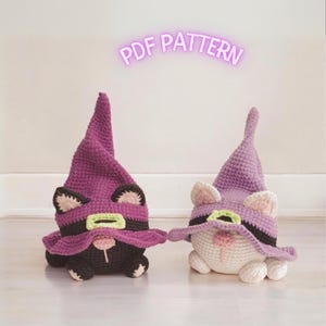 May include: Two crocheted witch cat plushies, one black and one white, wearing purple witch hats with green accents.  The hats have a black brim and the cats have pink ears.  The text "PDF PATTERN" is visible in the image.