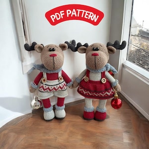 Può includere: Due ornamenti di renna all'uncinetto, uno con un vestito rosso e l'altro con un maglione rosso e bianco e una salopette. Entrambe le renne hanno la pelliccia marrone, gli occhi neri e il naso rosso. Le renne tengono in mano ornamenti rossi e argentati.