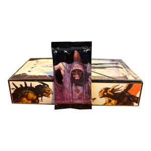May include: A sealed pack of "B.R.D.M. Fantasy Art Trading Cards" featuring a dark illustration of a robed figure. The pack is in front of a box with fantasy art illustrations on the sides and top.