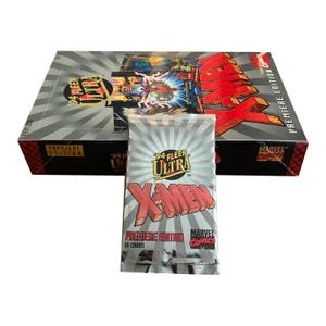 Könnte beinhalten: Eine versiegelte Packung '94 Fleer Ultra X-Men Premiere Edition Sammelkarten, mit einer Box im Hintergrund. Die Packung ist silberfarben mit rotem und gelbem Text. Die Box ist schwarz und silber mit roten Akzenten und dem Wort "X-Men" in großen roten Buchstaben.