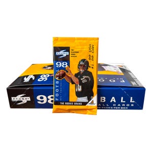 May include: A yellow and blue box of 1998 Score NFL football cards with a pack of cards in front. The pack features a football player and the text "The Rookie Brand". The box reads "Football All Cards 36 Packs Per Box".