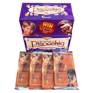 May include: A box of The Adventures of Pinocchio trading cards. The box is purple with a picture of Pinocchio on the front. There are four packs of cards in the image, each with a picture of a boy on the front. The text on the packs reads "The Adventures of Pinocchio Trading Cards".