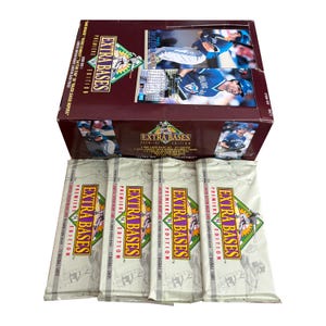 May include: A box of 1993 Extra Bases baseball cards, a popular brand of trading cards. The box is brown with a white and yellow label that says "Extra Bases Premiere Edition". The box is open and there are four packs of cards inside. Each pack has a white and yellow label that says "Extra Bases Premiere Edition".