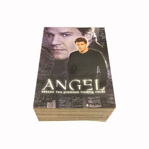 May include: A stack of Angel season two premium trading cards featuring a photo of David Boreanaz on the front. The cards are in a black and white colour scheme with a cityscape background.