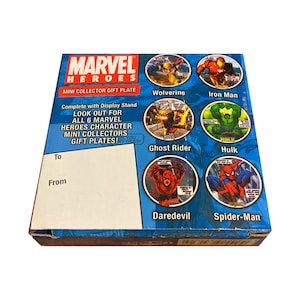May include: A blue and white box with a Marvel Heroes logo and images of six Marvel characters: Wolverine, Iron Man, Ghost Rider, Hulk, Daredevil, and Spider-Man. The box is a mini collector gift plate.