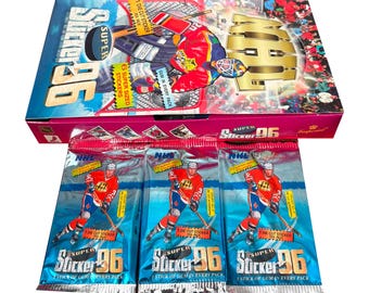 May include: A box of Super 96 hockey sticker packs. The box is pink and blue with the words "Super 96" in large letters. Three individual packs are visible, each with a hockey player image and the words "Super 96". Each pack contains a die cut sticker and a stick of gum.