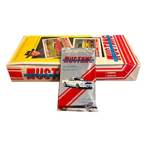 May include: A sealed pack of 10 premium collector's cards featuring the Carroll Shelby Signature Series of Mustang cars. The pack is silver with red and white stripes and features a white Mustang on a red background. The text on the pack reads "Mustang Cars, Carroll Shelby Signature Series, 10 Premium Collector's Cards".