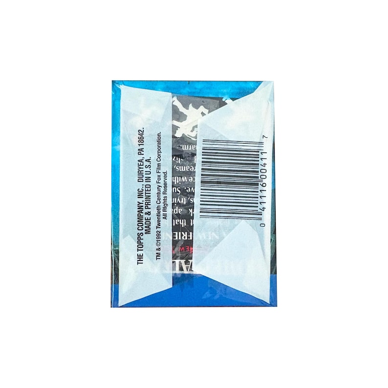 Op de afbeelding: Een verzegeld pakje ruilkaarten met een blauw en wit ontwerp. Het pakje heeft een barcode en de tekst "THE TOPPS COMPANY, INC., DURYEA, PA 18642. MADE & PRINTED IN U.S.A." en "NEW FRIE".