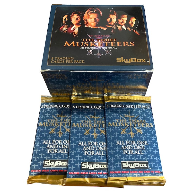 May include: Three packs of The Three Musketeers trading cards. Each pack features a blue background with gold accents and the text "The Three Musketeers" in gold lettering. The text "All for one and one for all" is also included in gold lettering. The SkyBox logo is in the bottom right corner of each pack.