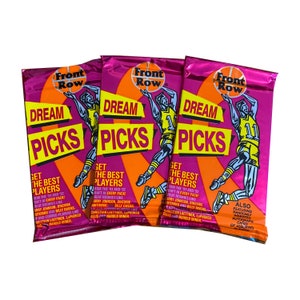 May include: Three pink and orange foil packs of basketball trading cards. Each pack features a basketball player in a red, white, and blue uniform with the text "Front Row Dream Picks" and "Get the Best Players" on the front.