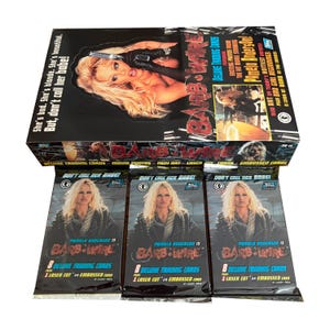 May include: A box set of Barb Wire deluxe trading cards featuring Pamela Anderson. The box has the movie title and a photo of Anderson. Three packs of cards are in front of the box, each with the movie title and Anderson's image. The text reads, "Don't call her babe!"