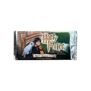May include: Sealed Harry Potter and the Sorcerer's Stone movie trading card pack. The packaging features Harry Potter with an owl, the movie title, and the text "7-CARD PACK". The background is a green and brown color.