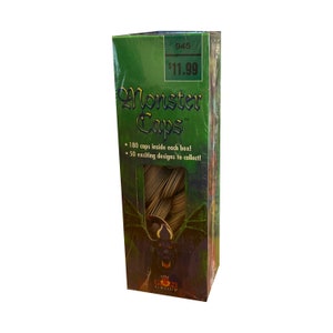 May include: A green box with a picture of a monster on it. The box says "Monster Caps" and "180 caps inside each box! 50 exciting designs to collect!" The box also has a price tag that says "$11.99".