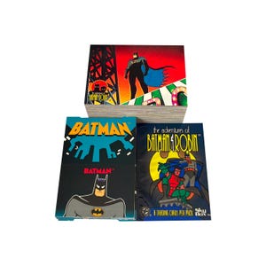 Pode incluir: Uma pilha de pacotes de cartas colecionáveis do Batman. Os pacotes apresentam Batman e Robin, com ilustrações e texto vibrantes. O pacote superior mostra Batman contra um fundo vermelho e laranja. Os outros pacotes têm um fundo preto.