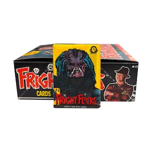 May include: A yellow pack of Fright Flicks bubble gum with cards featuring a Predator illustration, positioned in front of a black display box labeled Fright Flicks with a graphic of a character in a hat and red striped sweater, marked 48 CT.