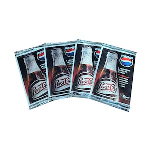 Könnte beinhalten: Vier ungeöffnete Packungen mit Pepsi Cola Sammelkarten. Jede Packung zeigt ein Vintage-Pepsi-Flaschendesign mit dem Pepsi-Logo. Die Packungen sind silberfarben mit roten und blauen Akzenten und dem Text "6 Premium Trading Cards".