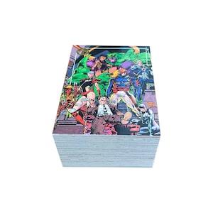 May include: A stack of comic trading cards featuring a group of colorful superheroes. The top card displays a vibrant illustration of several characters, including a large green figure and others in various costumes. The cards are stacked neatly against a white background.