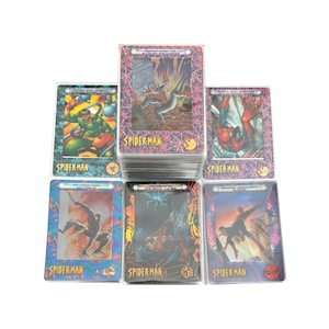 May include: A collection of Spider-Man trading cards. The cards feature various action scenes and character illustrations. The cards are in protective sleeves and have the Spider-Man logo. The cards are rectangular and have a glossy finish.
