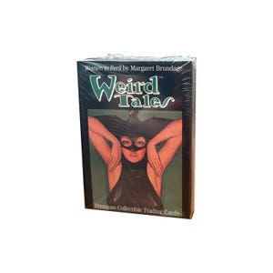 Könnte beinhalten: Eine versiegelte Schachtel mit "Weird Tales" Sammelkarten mit Kunstwerken von Margaret Brundage. Die Schachtel hat einen dunklen Hintergrund mit dem Titel in Weiß und Grün. Das Bild auf der Vorderseite zeigt eine Frau mit schwarzer Maske und Kleid.