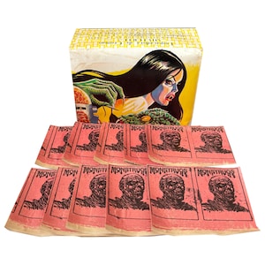 Könnte beinhalten: Ein Vintage-Monster-Kit mit einer Box, die eine Frau mit langen schwarzen Haaren und einer grünen Hand zeigt. Darunter befinden sich mehrere rosa Karten mit einer Monsterillustration und dem Wort "MONSTRUOS".