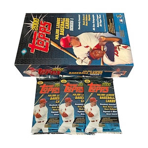 May include: A 2000 Topps Major League Baseball cards Series 1 hobby box and three matching unopened foil packs. The packaging features a blue background with a graphic of a baseball player in a red cap and white uniform holding a wooden bat.