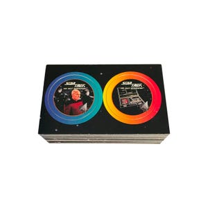 May include: A stack of Star Trek: The Next Generation trading cards. Each card features a circular design with images of characters and the show's logo. The background is black with a starry pattern.