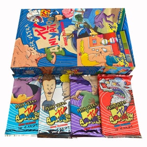 Pode incluir: Um conjunto de caixas de cartas colecionáveis Fleer Ultra MTV Animation. A caixa é azul com gráficos de desenhos animados e as palavras "MTV Animation" e "Fleer Ultra". Vários pacotes de cartas fechados são visíveis, cada um com arte de personagens única.