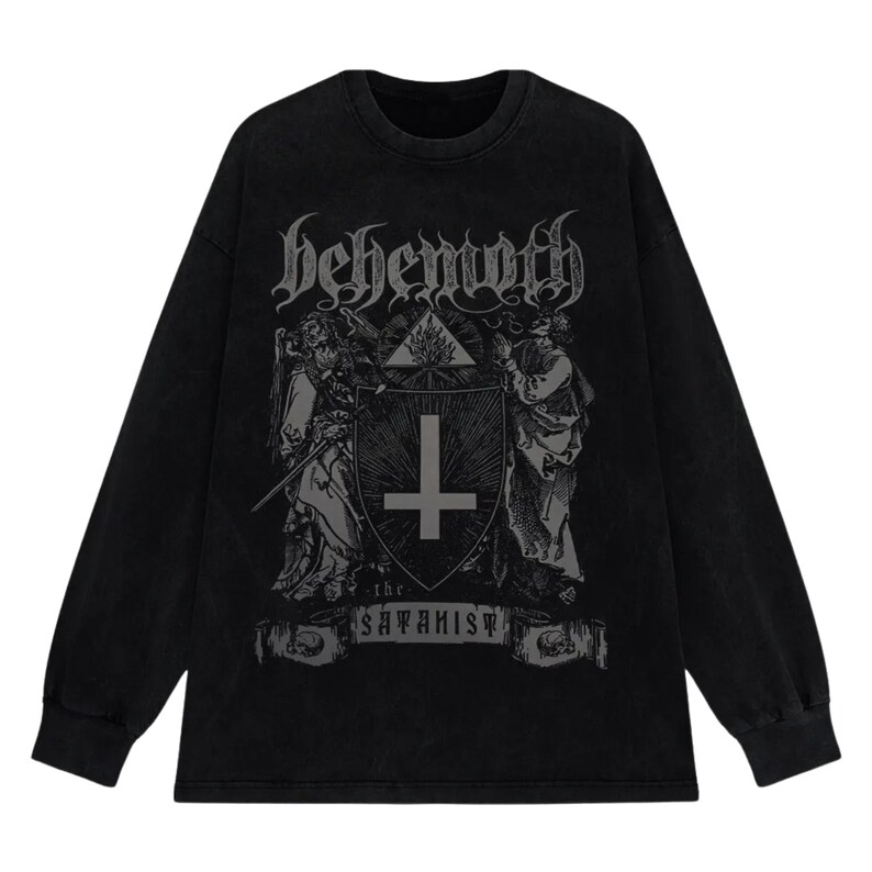 May include: Black long-sleeved top with a distressed graphic. The graphic features the word "behemoth" in gothic lettering, a shield with a cross, and the text "the satanist". The top has a crew neck and long sleeves.