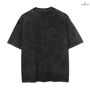 May include: Back view of a black, acid-wash t-shirt with short sleeves. The shirt has a textured appearance and a slightly oversized fit. The upper right corner features the text "Grunge Goth" in a stylized font.