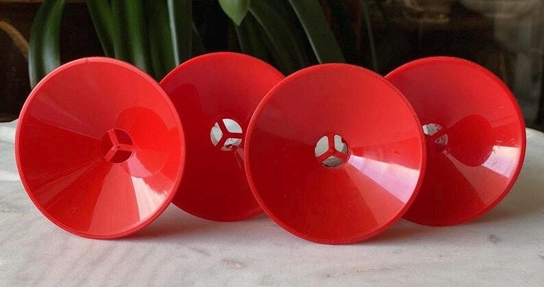 May include: Four bright red plastic funnels with a small hole in the center of each. The funnels are all the same size and shape.