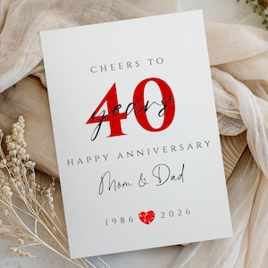 May include: White anniversary card with the text "Cheers to 40 years Happy Anniversary Mom & Dad 1986-2026". The number 40 is in red, with the word "years" in a cursive font. A red heart graphic is at the bottom.