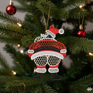 May include: Embroidered Christmas ornament shaped like Santa Claus with a red suit, black belt, and white beard. The ornament is hanging on a Christmas tree with red ornaments and lights.