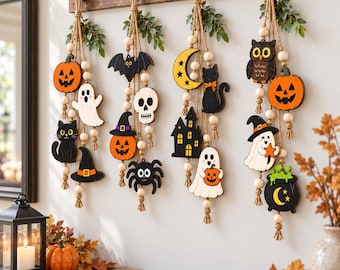 May include: Four vertical wall hangings featuring wooden Halloween-themed cutouts including pumpkins, ghosts, black cats, bats, skulls, a crescent moon, a haunted house, a spider, an owl, and a cauldron, strung with wooden beads and jute twine.