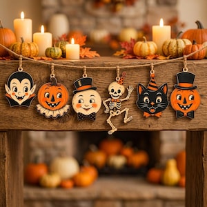 May include: A Halloween garland featuring six hanging wooden ornaments: a vampire, a jack-o'-lantern, a ghost in a top hat, a dancing skeleton, a black cat, and another jack-o'-lantern, all suspended from a rustic twine string.